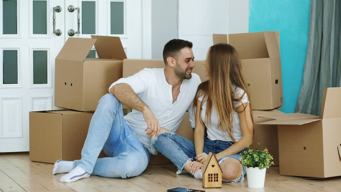 Happy couple surrounded by packed moving boxes in their new home